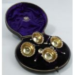 A cased set of four silver open salts, of circular form, with frilled edge, raised on three ball