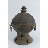 An Eastern terracotta covered urn, with embossed decoration to the cover, the base with chain and