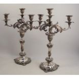 A pair of ornate rococco style silver plated three light candelabra, with scroll arms and raised
