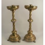 A pair of brass ecclesiastical style candlesticks, with circular drip tray, the twisted fluted