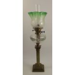 A 19th century brass oil lamp, raised on a Corinthian column with a stepped base, having a green