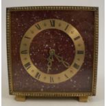 A Jaeger-Le Coultre gilt metal mantel clock, of square form with paint flicks to a burgundy ground