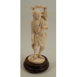 A 19th century carved ivory figure, of an Eastern man with harvested crops on his back, signed to