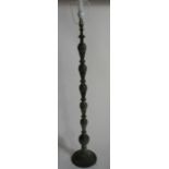 An Eastern metal lamp stand, showing copper patination, the knopped stem decorated with script,