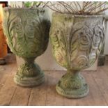 A pair of concrete garden urns, decorated with leaves, on a pedestal foot, height 25.5ins