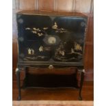 A black laquer cabinet on stand, with chinoisere decoration, having two doors opening to reveal a