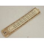 An Oriental bone pegging board, with carved decoration to the borders, length 8ins, width 1.5ins