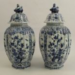 A pair of Delft vases, decorated with panels of birds and foliage with animal finials and marked