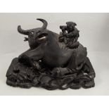 A carved wooden model of a water buffalo, with a figure astride, raised on a pierced rectangular
