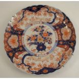 A circular Imari wall plate, decorated in the typical palette with iron reds and blues to a shaped