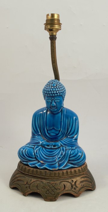 A table lamp, formed as a blue seated oriental deity, raised on a wooden base, height 13insCondition