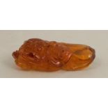 An amber coloured carving, of a mythical creature, length 2ins