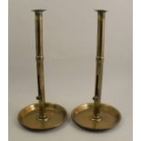 A pair of brass candlesticks, with slide for the candle, to a circular base, height 16.5ins