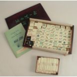 A cased Mah Jong set, the wooden box with slide lid containing bamboo and bone pieces, a rule book