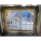 A large gilt picture frame, decorated with scrolls and flowers, picture aperture measurements