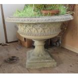 A large concrete garden urn, with weave effect to the body, raised on a pedestal base, height 23ins,
