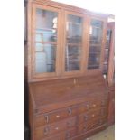 An oak estate cabinet, having three glazed doors over a bureau and fitted with 6 drawers with