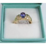 A tanzanite and diamond 18 carat gold ring, the oval cut stone with channel set brilliants to each