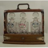 An oak three bottle tantalus, with silver plated mounts, with hinged flap to the front to release