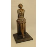 A Lorenzl patinated spelter table lighter, modelled as a woman wearing a flower dress leaning on a