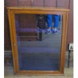 An early 20th century golden oak single door display case, with angled sides and velvet lined