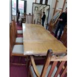 An Arts and Crafts style oak drop leaf dining table, raised on column supports, terminating in