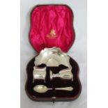 A cased silver christening set, comprising an egg cup, stand, spoon and napkin ring, with scroll