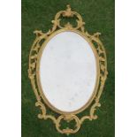 A gilt framed oval wall mirror, the frame formed as scrolls, leaves and flower heads, overall height