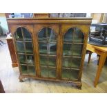 A walnut display cabinet, the glazed arched doors opening to reveal lined shelves