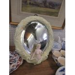 An oval porcelain framed mirror,