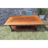 A large oak coffee table, of rectangular form, raised on turned legs with shelf under, 58.5ins x