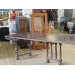 A CONTINENTAL EXTENDING DINING TABLE, WITH TURNED SUPPORTS, HAVING THREE EXTRA LEAVES, FULLY