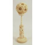 A 19th century carved ivory puzzle ball on stand, the stand carved with flowers and a bird, the ball