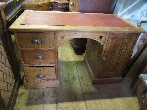 A pine desk, with leather top, having a bank of three drawers and a cupboard to each side, width