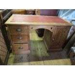 A pine desk, with leather top, having a bank of three drawers and a cupboard to each side, width