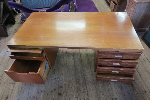 A large Gordon Russel teak twin pedestal desk, having a bank of drawers to one side and a fold