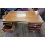 A large Gordon Russel teak twin pedestal desk, having a bank of drawers to one side and a fold