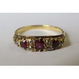 An early 20th century ruby and diamond ring, unmarked, the three oval cuts with pairs of diamonds