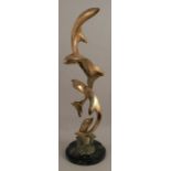A large polished brass sculpture, of four leaping dolphins, stamped JM 1988 5/12, on a stepped