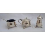 A silver three piece cruet set, raised on lion mask and paw supports, with two condiment spoons,