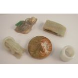Five Chinese and oriental carved items of jade and hardstone, comprising a belt hook, a figure of