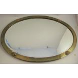 A late 19th century Arts and Crafts oval brass wall mirror, having hammered finish, four oval
