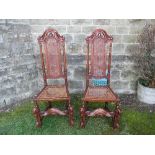 A pair of  chairs, the high carved backs with cane panel and seat, on carved front legs united by