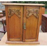 An Edwardian oak table top cabinet, with carved decoration to the pair of doors, 20ins x 13ins x
