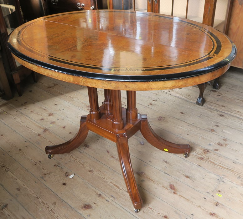 An oval walnut loo table, with ebonised and satinwood inlay, raised on a modern mahogany base,