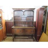 An oak dresser, the rack back with cupboard and shelves, the base fitted with drop flaps, width