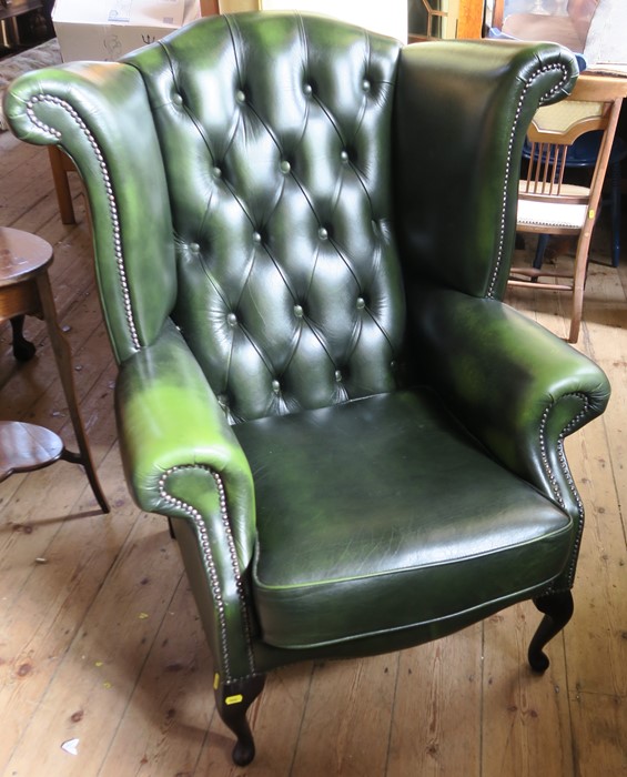 A modern green leatherette wing armchair, with button back, raised on cabriole legs, with fire