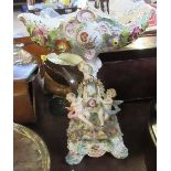 A continental porcelain centrepiece, with pierced shaped basket, the column supported by putti and
