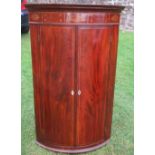A 19th century mahogany barrel front corner cabinet, the frieze with inlaid decoration, the pair