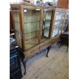 A Georgian style walnut glazed display cabinet, fitted with two drawers below, raised on a stand,